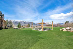 View of green lawn featuring a mountain view and a patio