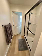 Full bath with light wood finished floors and a shower stall