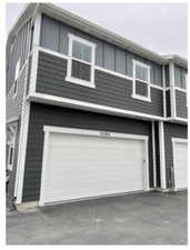 View of side of home featuring an attached garage, board and batten siding, and driveway