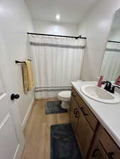 Full bath with light wood-type flooring, a shower with curtain, vanity, and a textured ceiling