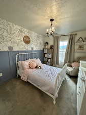 Bedroom with wallpapered walls, a textured ceiling, carpet flooring, and a chandelier