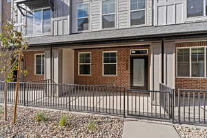 Entrance to property featuring brick siding and a shingled roof