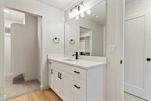 Bathroom with a walk in closet, light wood-type flooring, vanity, and a textured ceiling