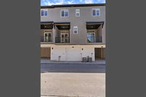 Back of property featuring stucco siding, a balcony, and a garage