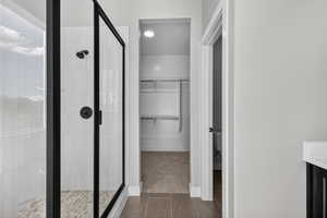 Bathroom featuring a spacious closet, vanity, and a shower stall