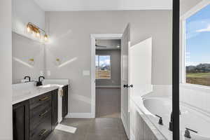 Full bathroom featuring a bath, dark tile patterned floors, and vanity