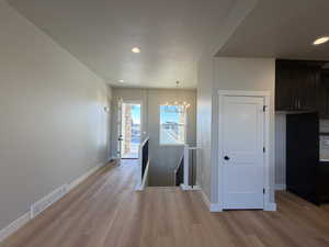 Hall featuring an upstairs landing, light wood-style flooring, a chandelier, recessed lighting, and a textured ceiling