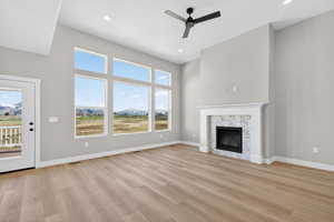 Unfurnished living room featuring light wood finished floors, a glass covered fireplace, ceiling fan, recessed lighting, and a mountain view