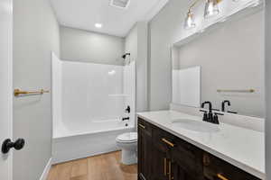 Full bath featuring vanity, shower / bathtub combination, and light wood-style flooring