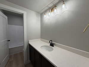 Bathroom featuring vanity, a textured ceiling, dark wood-type flooring, and washtub / shower combination