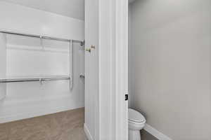 Bathroom with a walk in closet and light colored carpet