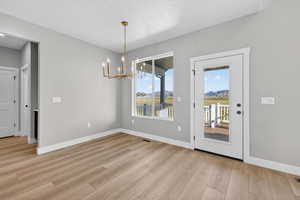 Unfurnished dining area with a chandelier and light wood finished floors
