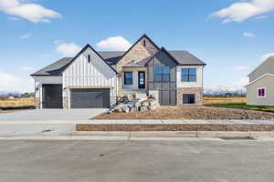 View of front of home featuring concrete driveway, board and batten siding, roof with shingles, stone siding, and a garage
