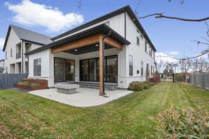Back of property with a fenced backyard, board and batten siding, a patio area, and brick siding