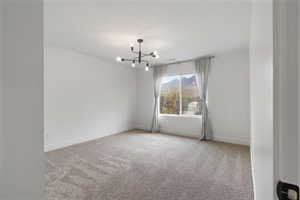 Unfurnished room with light colored carpet, a chandelier, and a mountain view