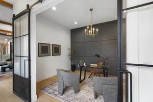 Office with a chandelier, a decorative wall, wood finished floors, a barn door, and recessed lighting