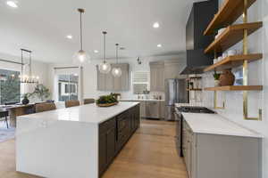 Kitchen featuring high end appliances, light stone counters, backsplash, open shelves, and light wood finished floors