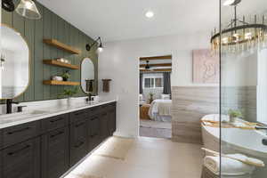 Full bathroom featuring double vanity, a freestanding bath, ensuite bath, light tile patterned flooring, and recessed lighting