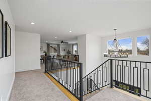 Hall with an upstairs landing, recessed lighting, light colored carpet, and a chandelier