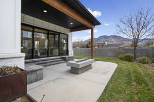 Fenced backyard featuring a mountain view, a patio area, and a fire pit