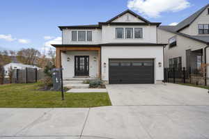 Modern farmhouse featuring a porch, driveway, a garage, brick siding, and board and batten siding