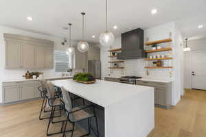 Kitchen with gray cabinets, decorative light fixtures, a kitchen breakfast bar, open shelves, and recessed lighting