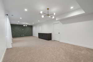 Basement featuring a chandelier, light carpet, and recessed lighting