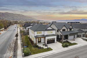 View of front of home with concrete driveway, a mountain view, covered porch, and a shingled roof