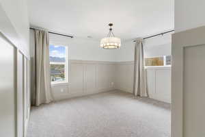 Carpeted spare room with a decorative wall and wainscoting