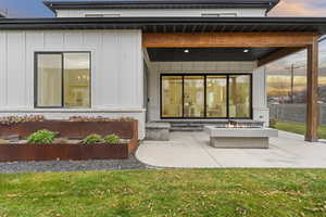 Back of house featuring board and batten siding, a patio, and an outdoor fire pit