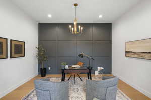 Office with a decorative wall, wood finished floors, and a chandelier