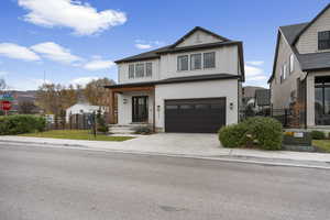 View of front facade featuring an attached garage, driveway, and brick siding