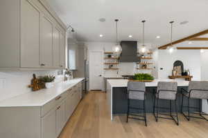 Kitchen with open shelves, gray cabinets, light wood-type flooring, backsplash, and a breakfast bar