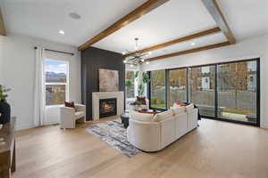 Living area featuring beamed ceiling, a large fireplace, light wood finished floors, a chandelier, and recessed lighting