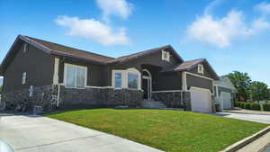 Single story home featuring stone siding, a front lawn, driveway, and stucco siding
