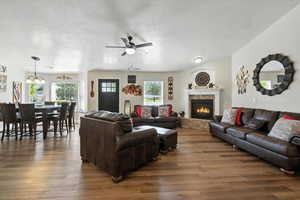 Living area with ceiling fan, wood finished floors, a fireplace, healthy amount of natural light, and a textured ceiling