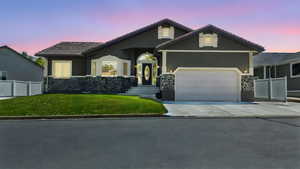 View of front of house featuring stone siding, driveway, a garage, stucco siding, and a tile roof