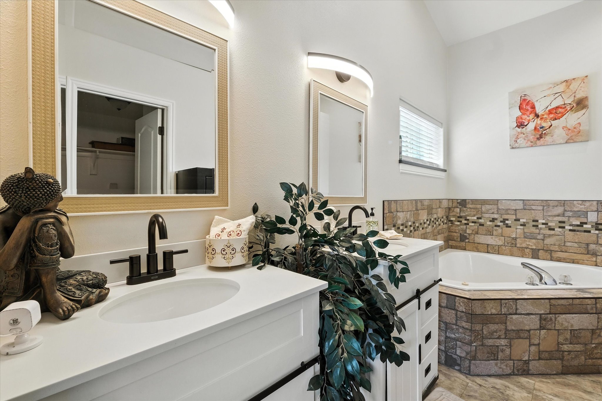 Full master bathroom featuring a garden tub, vanity, and lofted ceiling. Separate shower and toilet area.