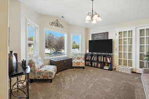 Living area with carpet flooring, lofted ceiling, a chandelier, and healthy amount of natural light