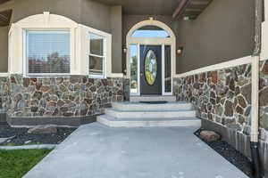 Doorway to property featuring stone siding and stucco siding