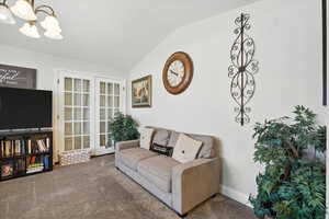 Carpeted living room with a chandelier and lofted ceiling