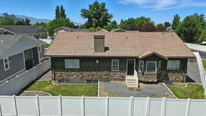 View of back of home with a fenced backyard, stone siding, and a tiled roof