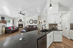 Kitchen with stainless steel dishwasher, ceiling fan, light wood finished floors, tasteful backsplash, and vaulted ceiling