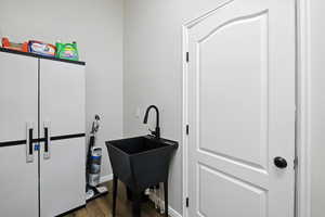 Laundry area with wood finished floors and a sink