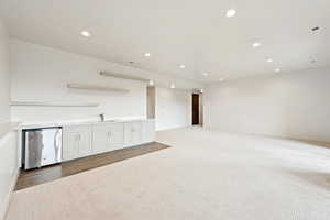 Kitchen with recessed lighting, stainless steel refrigerator, light carpet, light countertops, and white cabinets