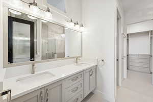 Bathroom with a spacious closet, double vanity, and a stall shower