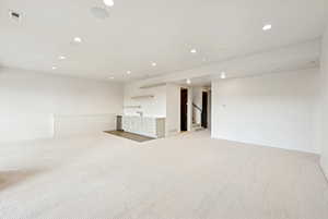 Empty room featuring recessed lighting, light carpet, and stairway