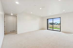 Empty room with light colored carpet and recessed lighting