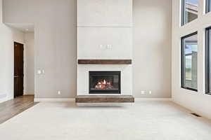 Unfurnished living room with a glass covered fireplace, a towering ceiling, and carpet