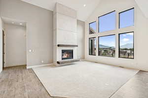 Unfurnished living room with wood finish floors, high vaulted ceiling, a large fireplace, recessed lighting, and a mountain view